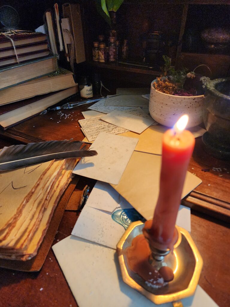 orange candle burning on archivist apprentice's messy desk